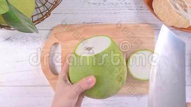 一位年轻的亚洲妇女正在家里的<strong>厨房</strong>里切新鲜的柚子。<strong>厨房</strong>在明亮的白色木桌和<strong>砧板</strong>上，俯视图